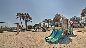 A beach with a playground, including slides and a wooden playhouse. - Welcome to Serinity on the Beach (Myrtle Beach)