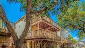 A wooden building with a balcony, surrounded by trees and a clear sky. - Welcome to Serinity on the Beach (Myrtle Beach)