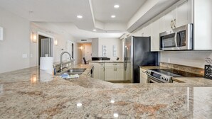 Una cocina moderna con encimeras de granito, electrodomésticos de acero inoxidable y una isla central.