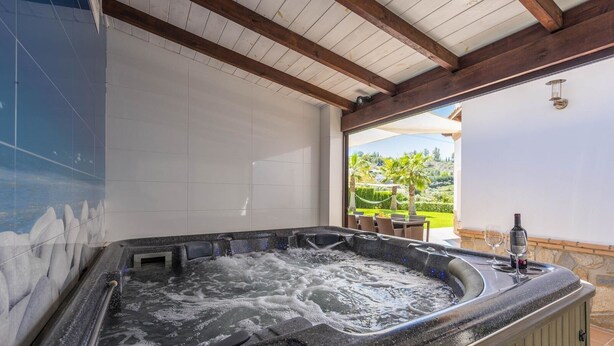 Un bain à remous avec vue sur un jardin aménagé et un patio doté d’un espace salon extérieur.