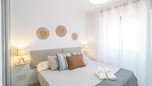 A neatly made bed with pillows, a bedside lamp, and a wall-mounted decorative item. - Villa Universal Beauty Resort Torrox by Ruralidays (Málaga)