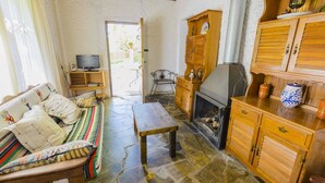 A cozy living room with a sofa, a wooden cabinet, a fireplace, and a television. - Barranco de La Salud - El Porche Nevada by Ruralidays (Granada)