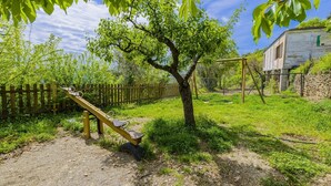 A playground with a seesaw and a swing set, surrounded by a wooden fence and greenery. - Barranco de La Salud - El Porche Nevada by Ruralidays (Granada)