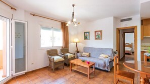 A living room with a sofa, two wicker chairs, a coffee table, a lamp, and a dining table. - Apartamento Cañada del Barco Torrox by Ruralidays (Málaga)