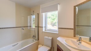 Ein Badezimmer mit Duschkabine, Toilette, Waschbecken und einem Fenster für natürliches Licht.