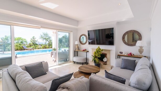 A modern living room with a pool view, a flat-screen TV, and a fireplace. - Villa Latina Golf Arcos de la Frontera by Ruralidays (Cádiz)