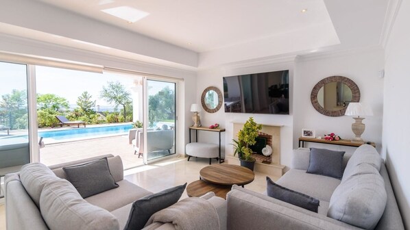 A modern living room with a pool view, a flat-screen TV, and a fireplace. - Villa Latina Golf Arcos de la Frontera by Ruralidays (Cádiz)