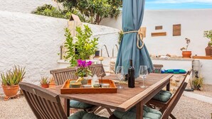 A wooden table set with a tray, wine glasses, and a bottle, surrounded by potted plants and a blue curtain. - Casa Shyshka Periana by Ruralidays (Málaga)