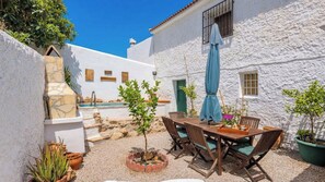 A white building with a patio area, outdoor seating, and potted plants. - Casa Shyshka Periana by Ruralidays (Málaga)