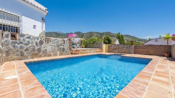 A rectangular swimming pool with stone walls and a tiled deck, surrounded by a mountainous landscape. - Villa Aránzazu Nerja by Ruralidays (Málaga)