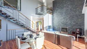 A modern interior with a staircase, a dining area, a living space with a fireplace, and a stone accent wall. - Idem Rural Baza by Ruralidays (Granada)