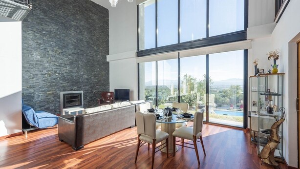 A modern living space with a stone wall, a dining area with a glass table, and a view of the outdoors. - Idem Rural Baza by Ruralidays (Granada)