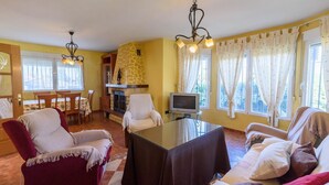 A living room with a fireplace, a television, and a dining area with a table and chairs. - Casa Rural cerca de Granada Otura by Ruralidays (Granada)
