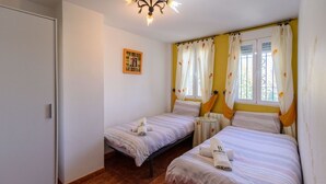 A bedroom with two beds, a small table, and a framed picture on the wall. - Casa Rural cerca de Granada Otura by Ruralidays (Granada)