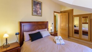 A hotel room with a large bed, wooden headboard, two bedside lamps, a painting above the bed, and a wardrobe with a mirror. - Casa Rural cerca de Granada Otura by Ruralidays (Granada)