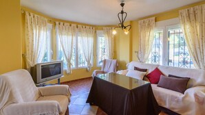 A cozy living room with a sofa, armchairs, a glass coffee table, and a television. - Casa Rural cerca de Granada Otura by Ruralidays (Granada)