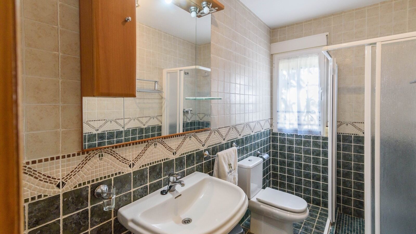 Casa de banho com lavatório, sanita e chuveiro.
