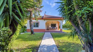 Uma casa com telhado de cerâmica, varanda coberta e um caminho de paralelepípedos até a entrada.
