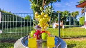 Exposição de frutas e sucos com uma bandeja de metal, uma tigela de vidro com uvas e dois copos de suco amarelo.