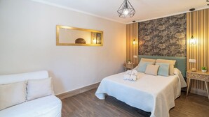Hotellihuone, jossa on sänky, oleskelualue, peili ja seinä, jossa on pystysuorat puupaneelit.