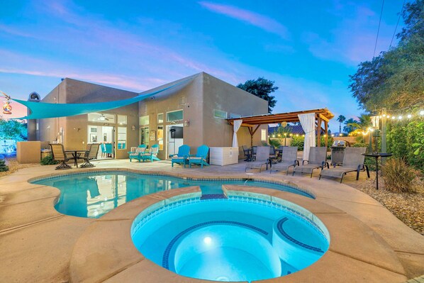Une maison moderne dotée d’une piscine, d’un espace salon extérieur et d’un patio couvert.