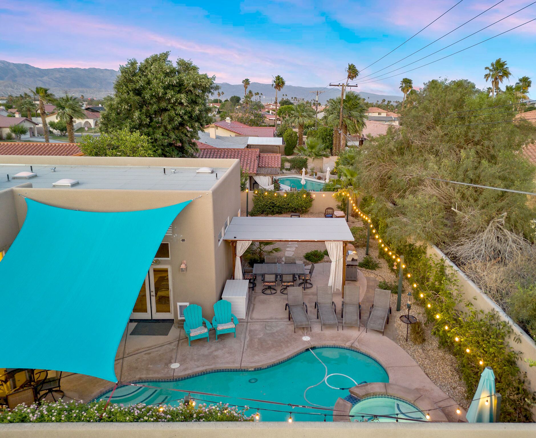 A residential area with a swimming pool, outdoor seating, and a view of distant mountains.