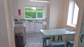Een kleine keuken met witte kasten, een spoelbak en een raam met uitzicht op groen.