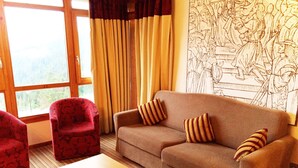 Ein Zimmer mit einem braunen Sofa, einem roten Sessel und einem Holztisch.