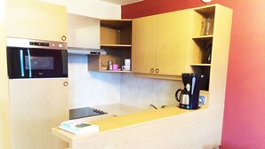 Eine kompakte Küche mit Einbauofen, Kaffeemaschine und Holzausstattung.