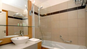 Ein modernes Badezimmer mit einer gläsernen Dusche, einer weißen Badewanne und einem Waschtisch mit großem Spiegel.