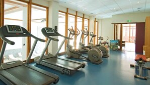 Un gimnasio con cintas de correr, elípticas y una bicicleta estática.