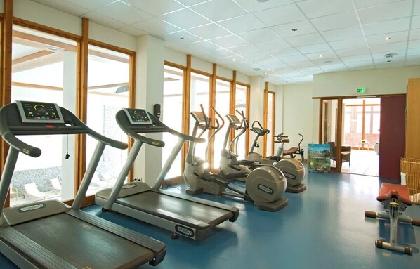 Une salle de sport équipée de tapis de course, d’elliptiques et d’un vélo d’appartement.