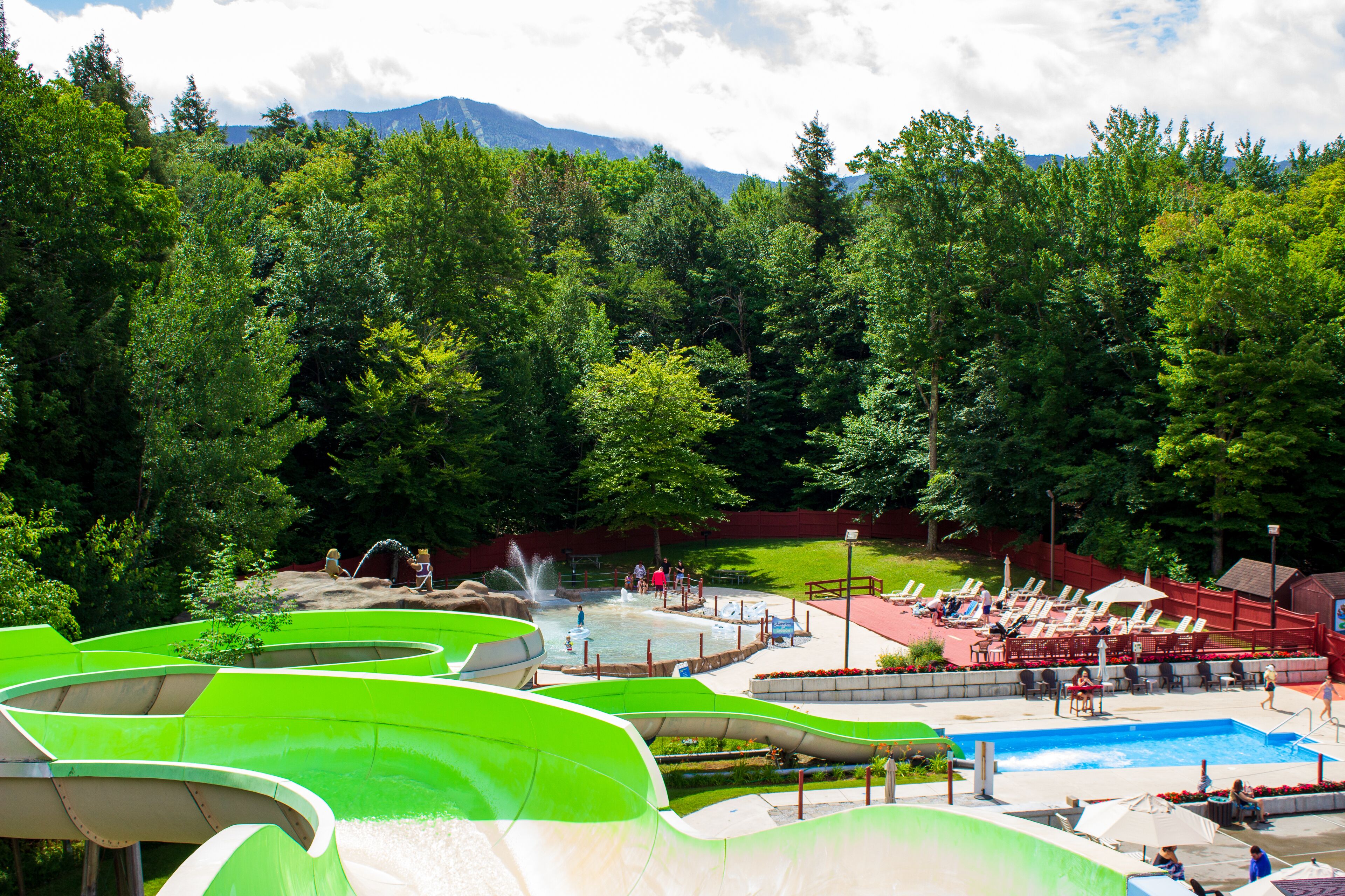 A water park with slides and a pool area surrounded by trees.