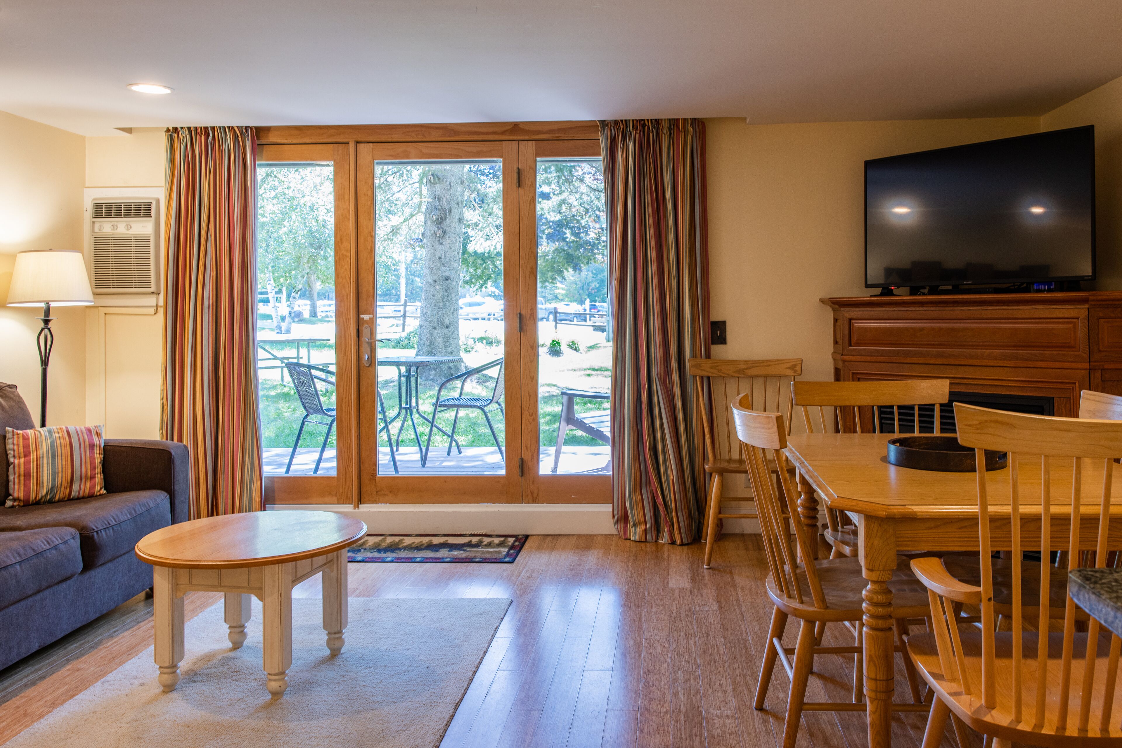 A living room with a sofa, a coffee table, a TV on a wooden cabinet, and a dining area with a table and chairs.