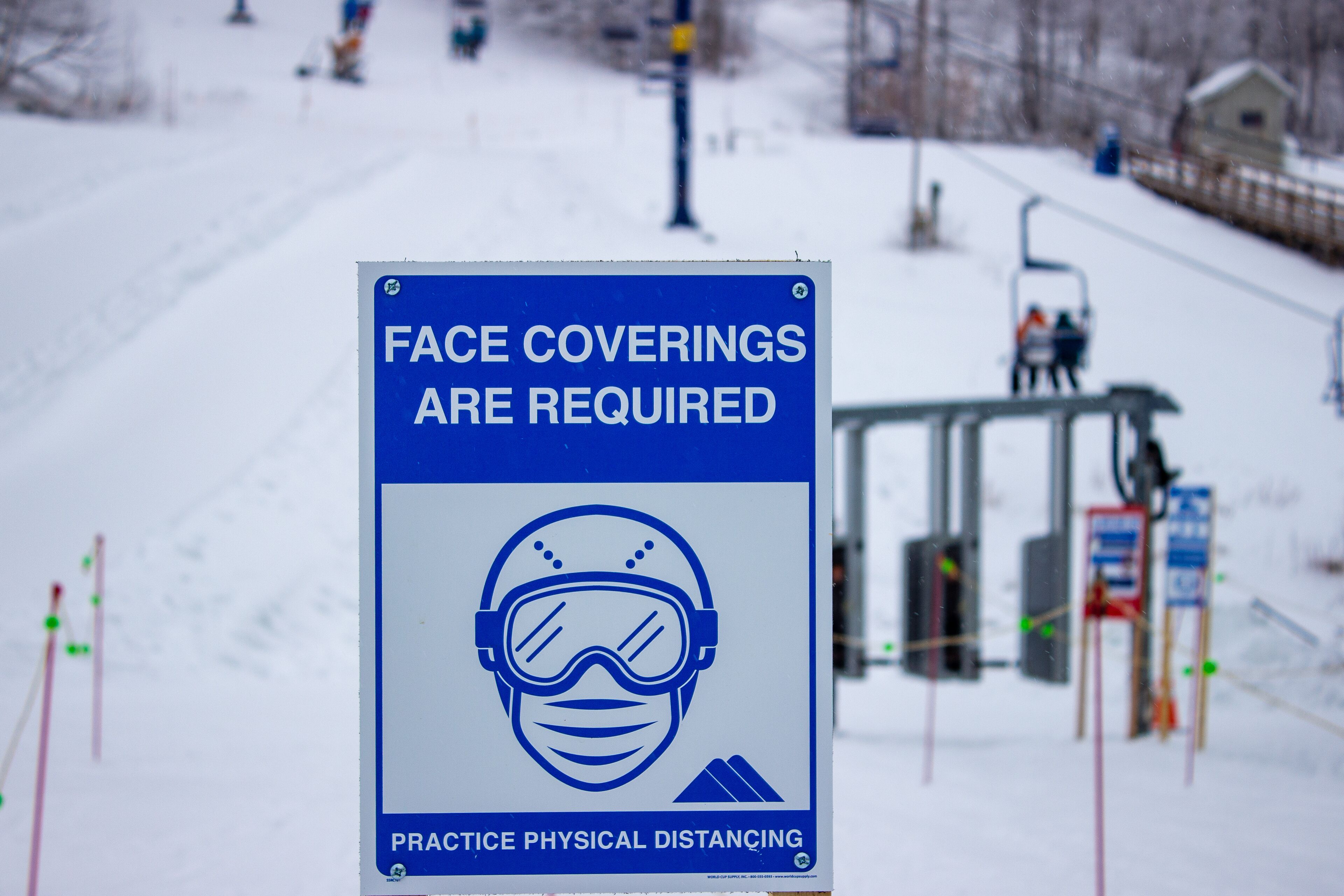 A sign indicating face coverings are required and physical distancing is practiced.