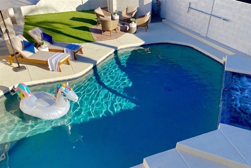 A swimming pool with lounge chairs and a grassy area.