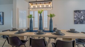 Een moderne eetruimte met een lange tafel, zwarte stoelen en decoratieve vazen met planten.