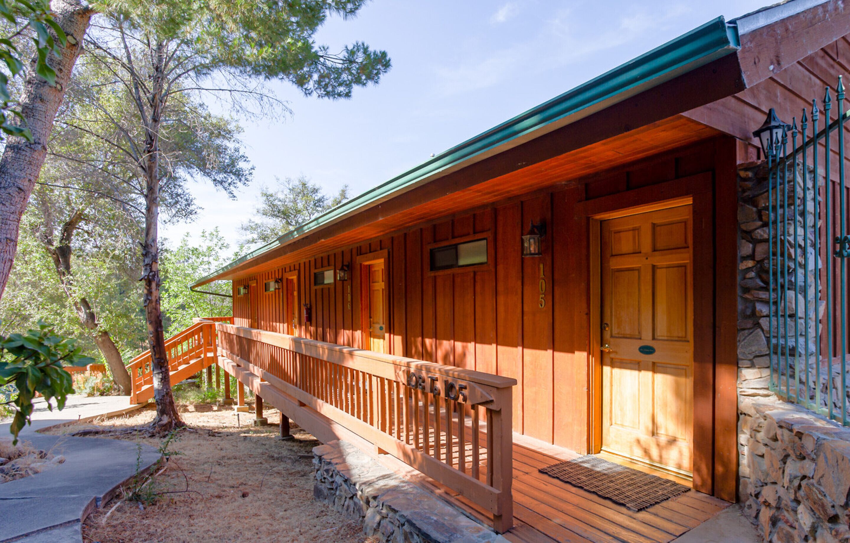 Une cabane en bois dotée d’une terrasse en bois, d’un mur en pierre et d’un escalier en bois menant à l’entrée.