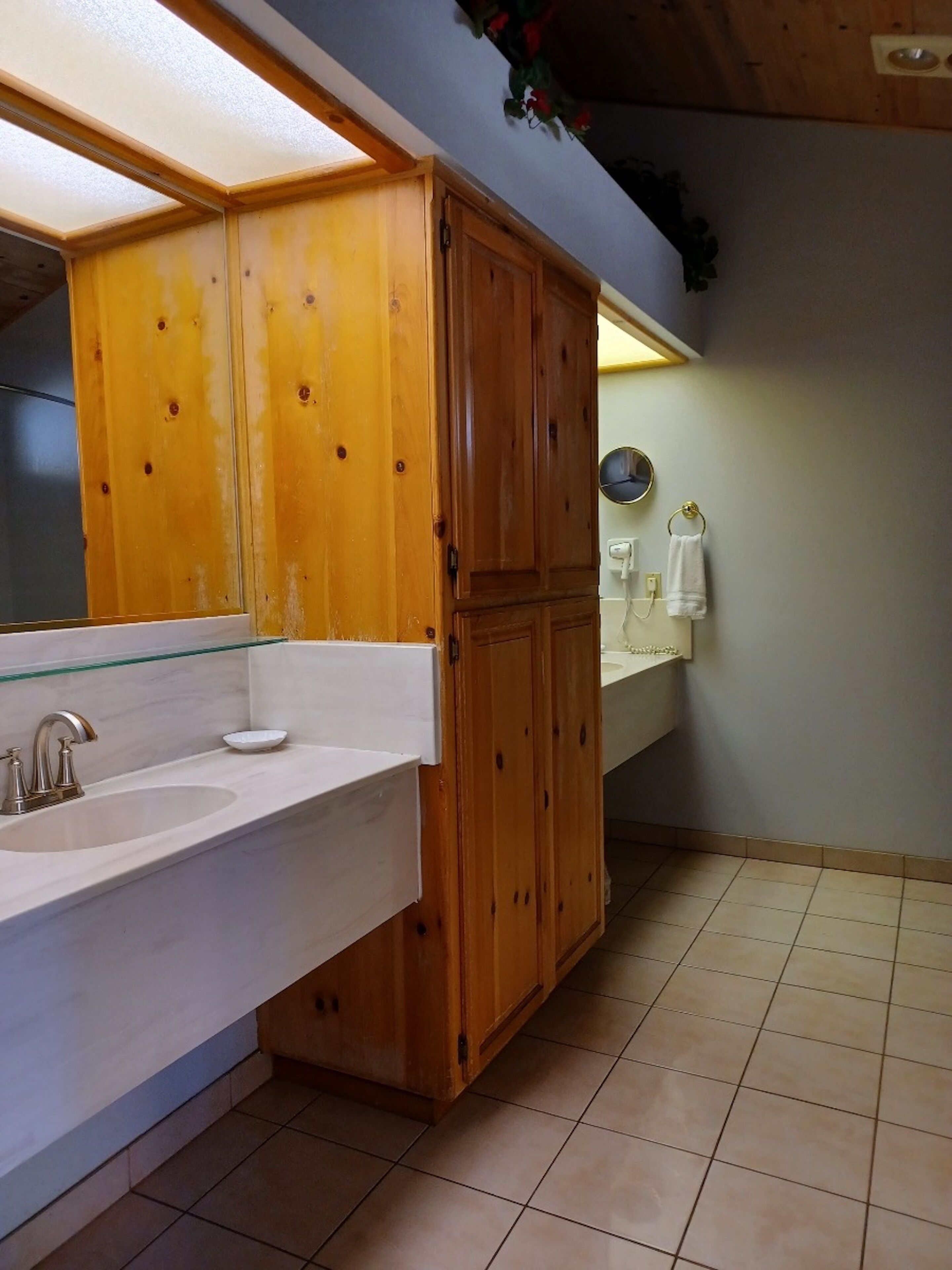 A bathroom with wooden cabinets, a white sink, and a mirror.