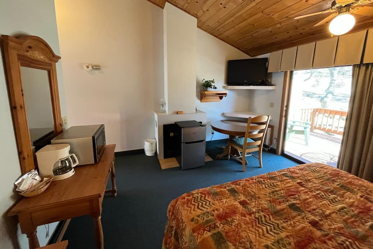 A room with a bed, a desk, a chair, a television, and a ceiling fan.