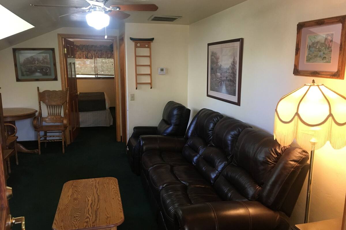A living room with a leather sofa, a wooden coffee table, a lamp, and framed pictures on the walls.