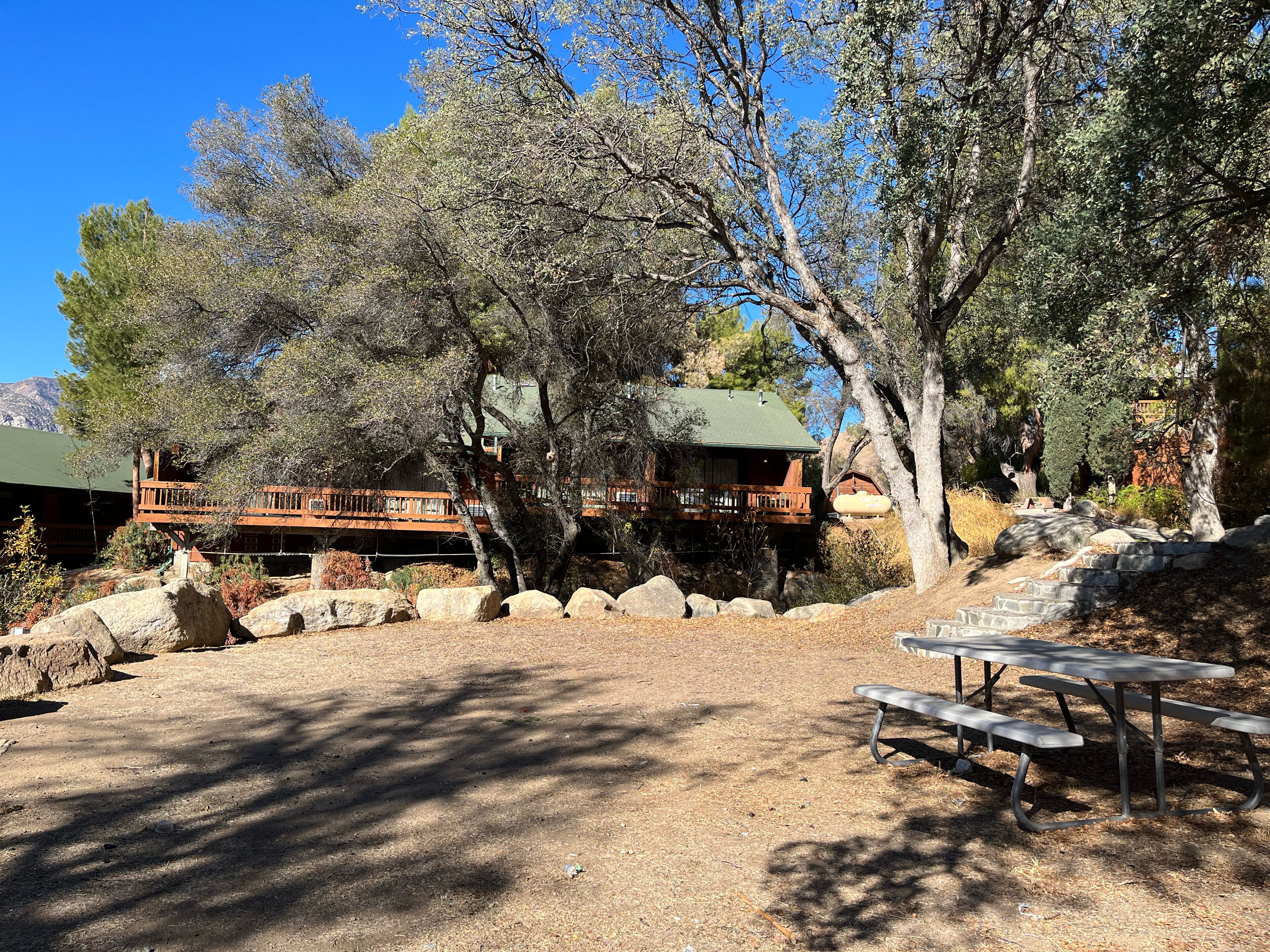 A lodge with a wooden deck and a stone pathway leading to a picnic table.