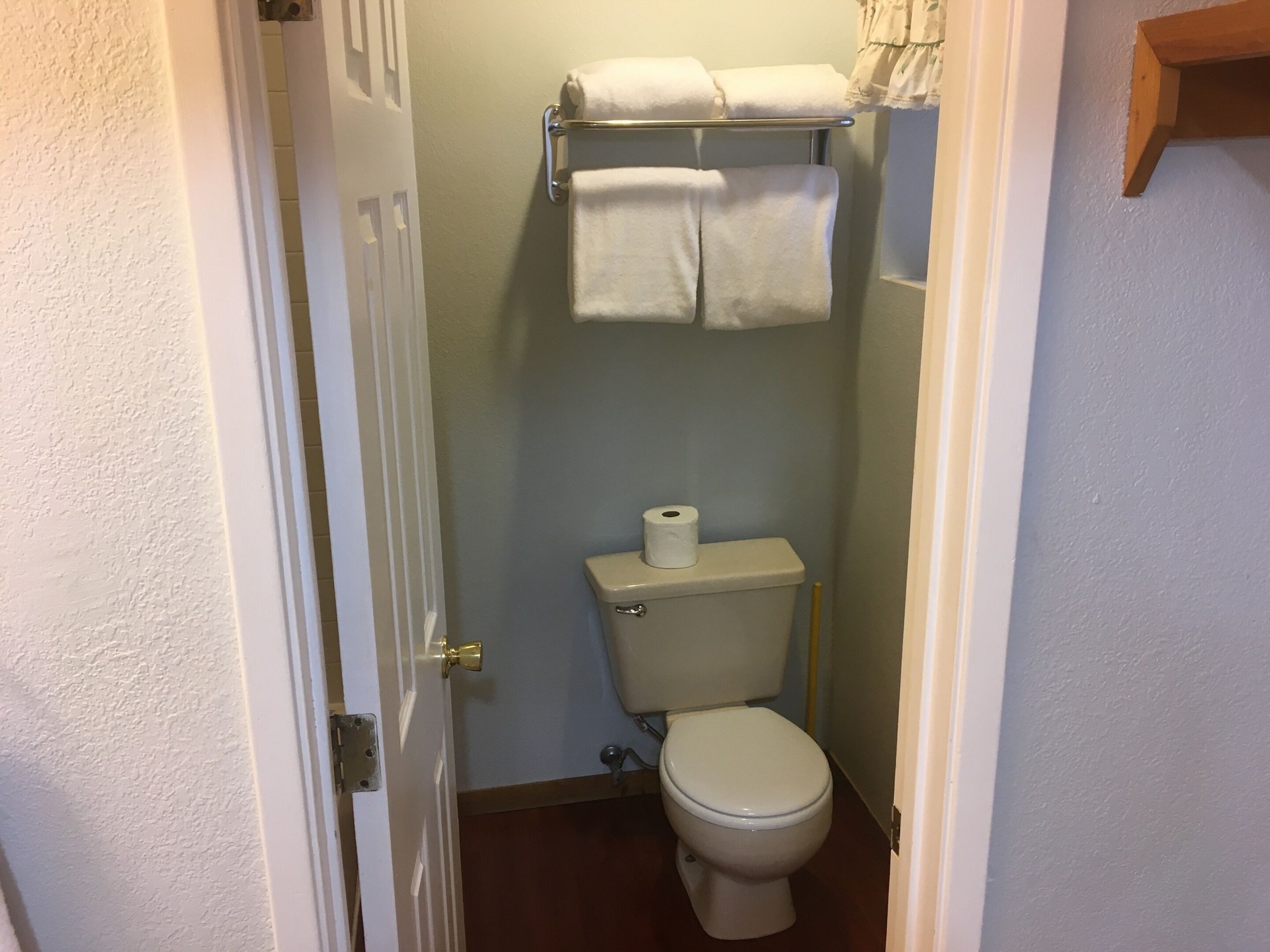 Une petite salle de bain comprenant des toilettes, un porte-serviettes avec deux serviettes et un rouleau de papier toilette.