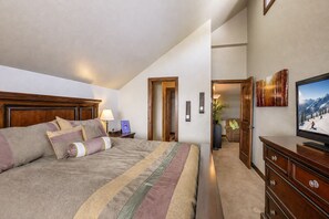 A bedroom with a large bed, a TV, a dresser, and a hallway leading to another room. - Luxury Condo, 1 Mi. to Ski Resort, Community Hot Tub (Durango)