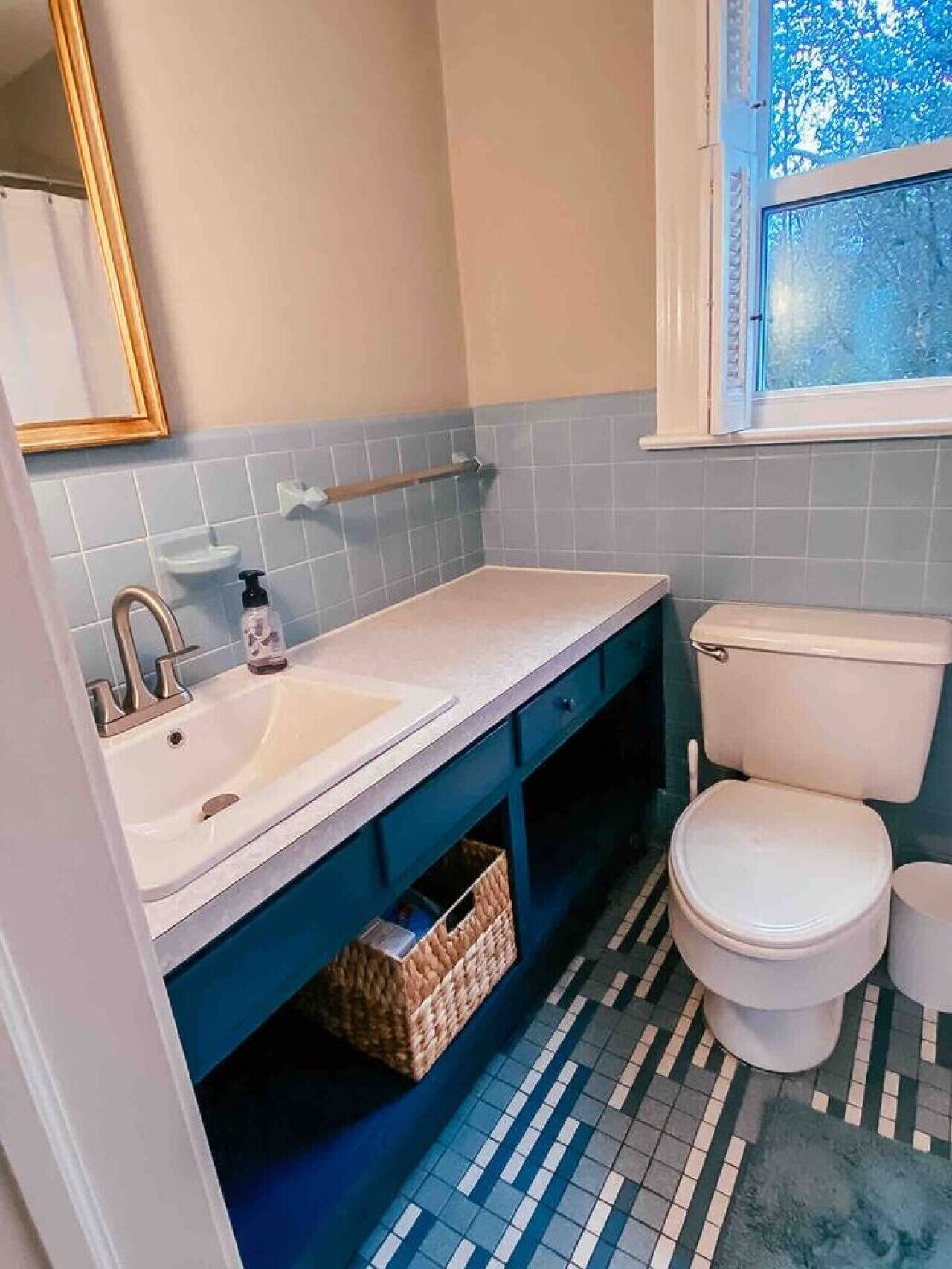 A bathroom with a white sink, a toilet, and a window with a view of trees.