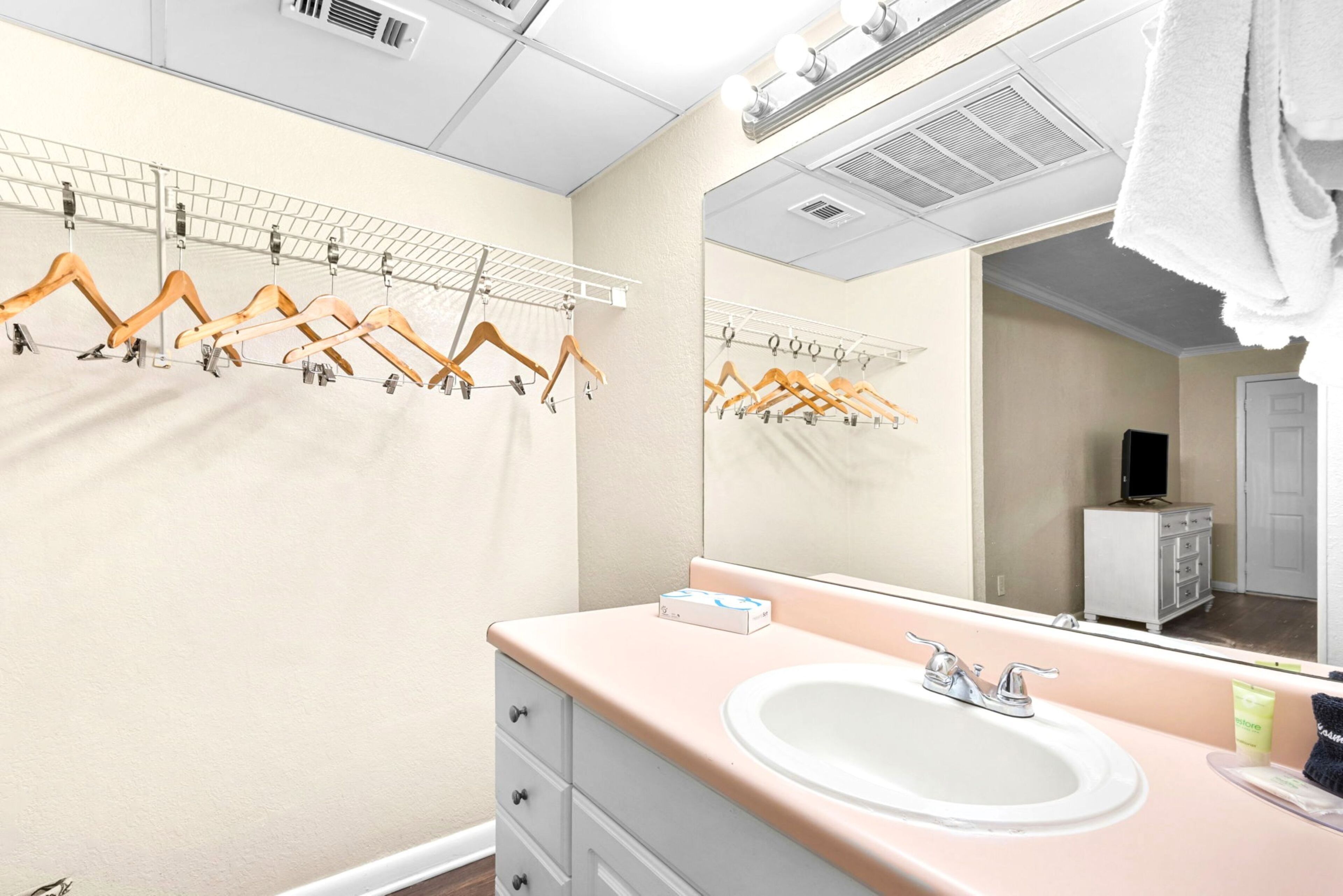 Un bagno con lavandino, specchio, porta asciugamani e mobiletto.