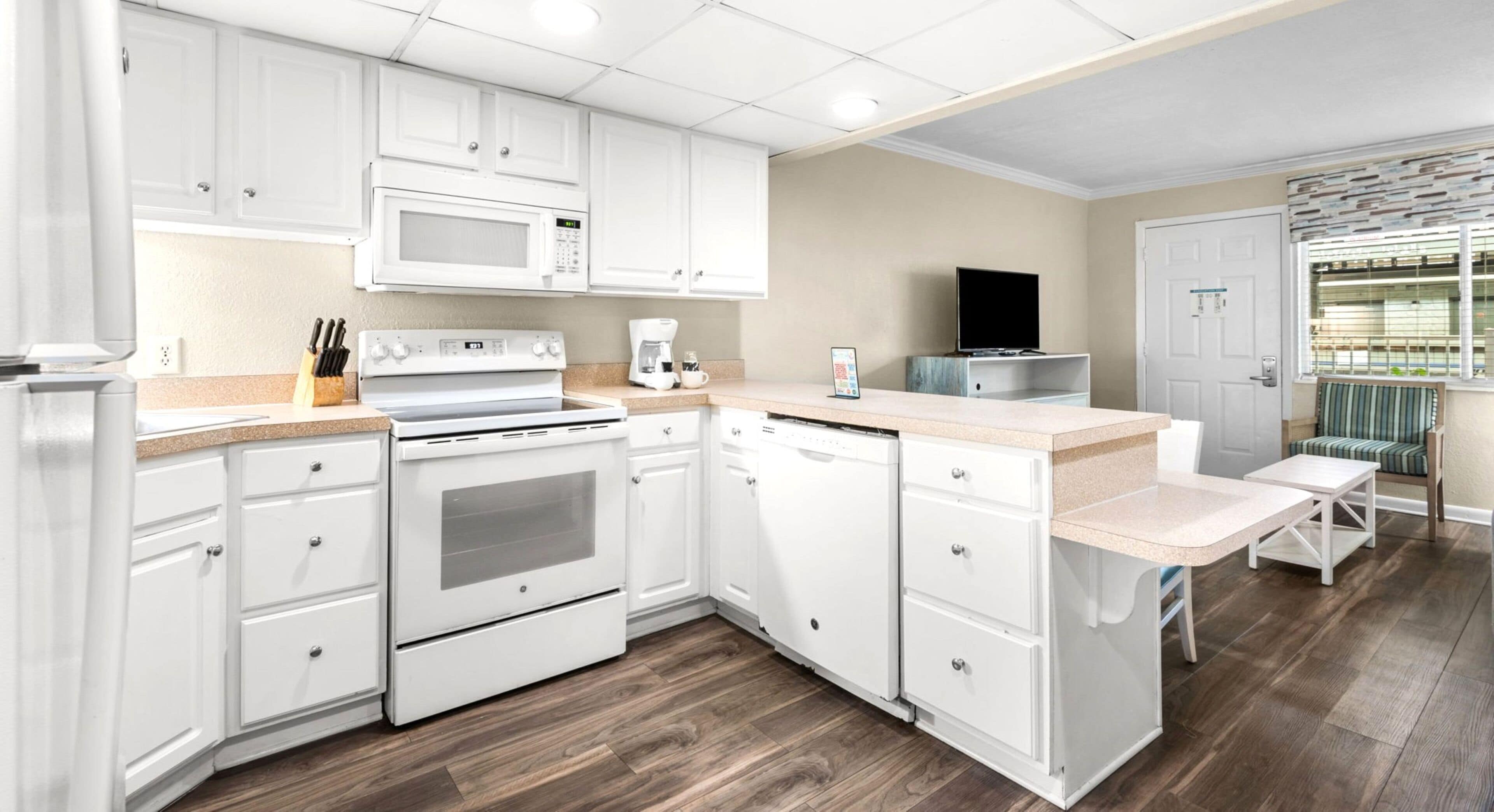 A modern kitchen with white cabinetry, a microwave, stove, and dishwasher.