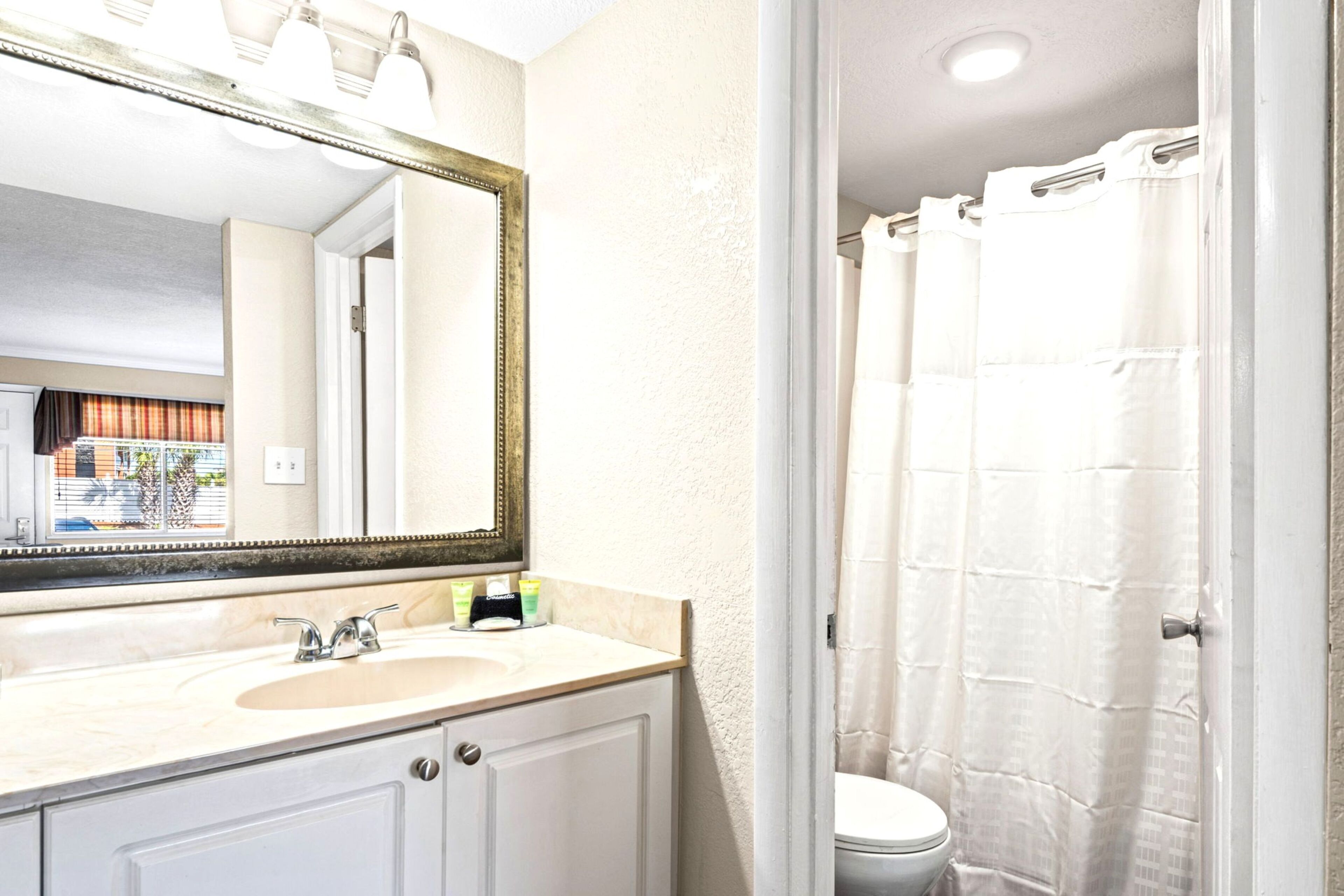A bathroom with a sink, mirror, and shower curtain.