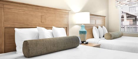 Et hotelværelse med to senge, et træhovedgærde, en lampe og et vindue med persienner.