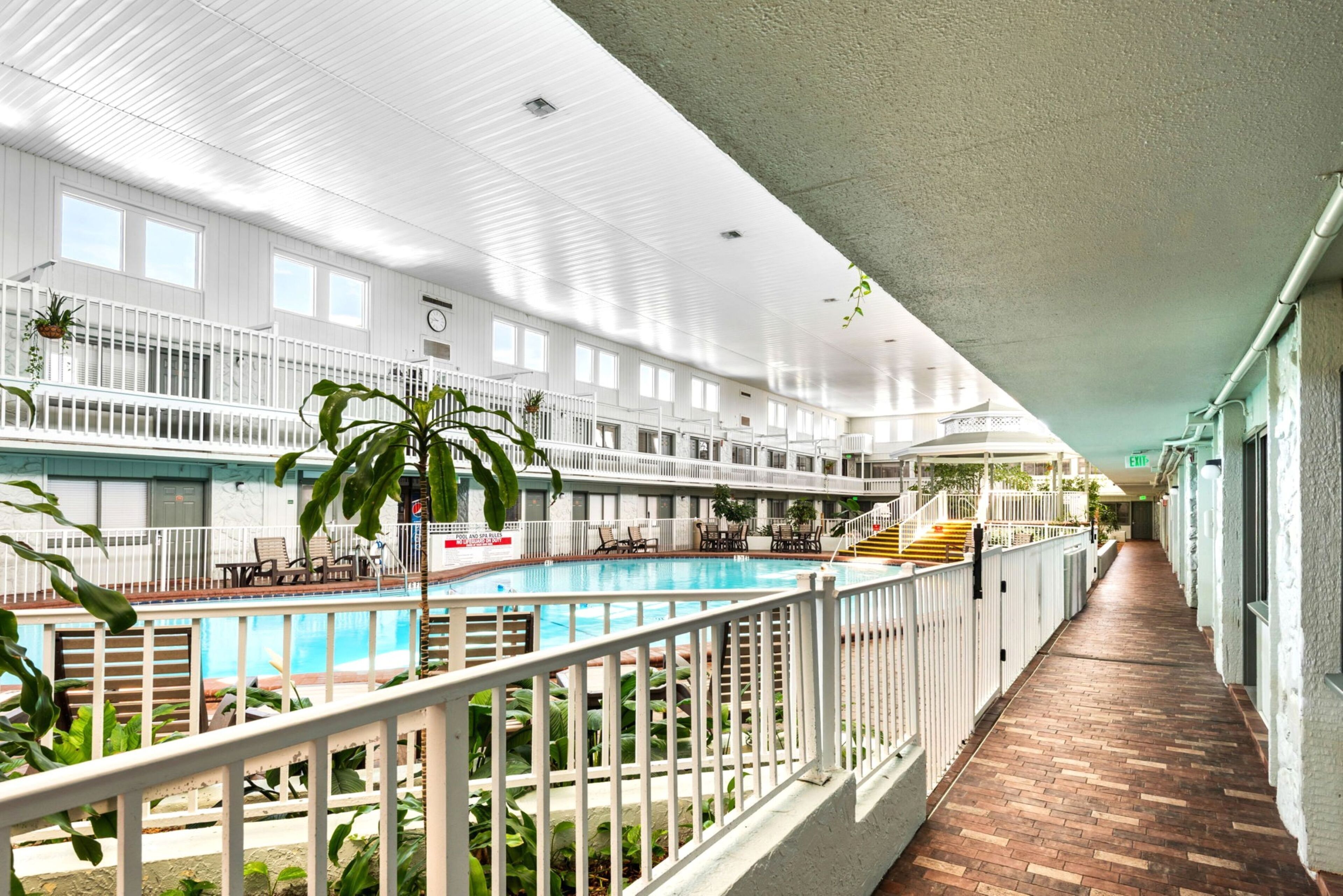 An indoor swimming pool with a brick floor, white railings, and multiple levels with balconies.